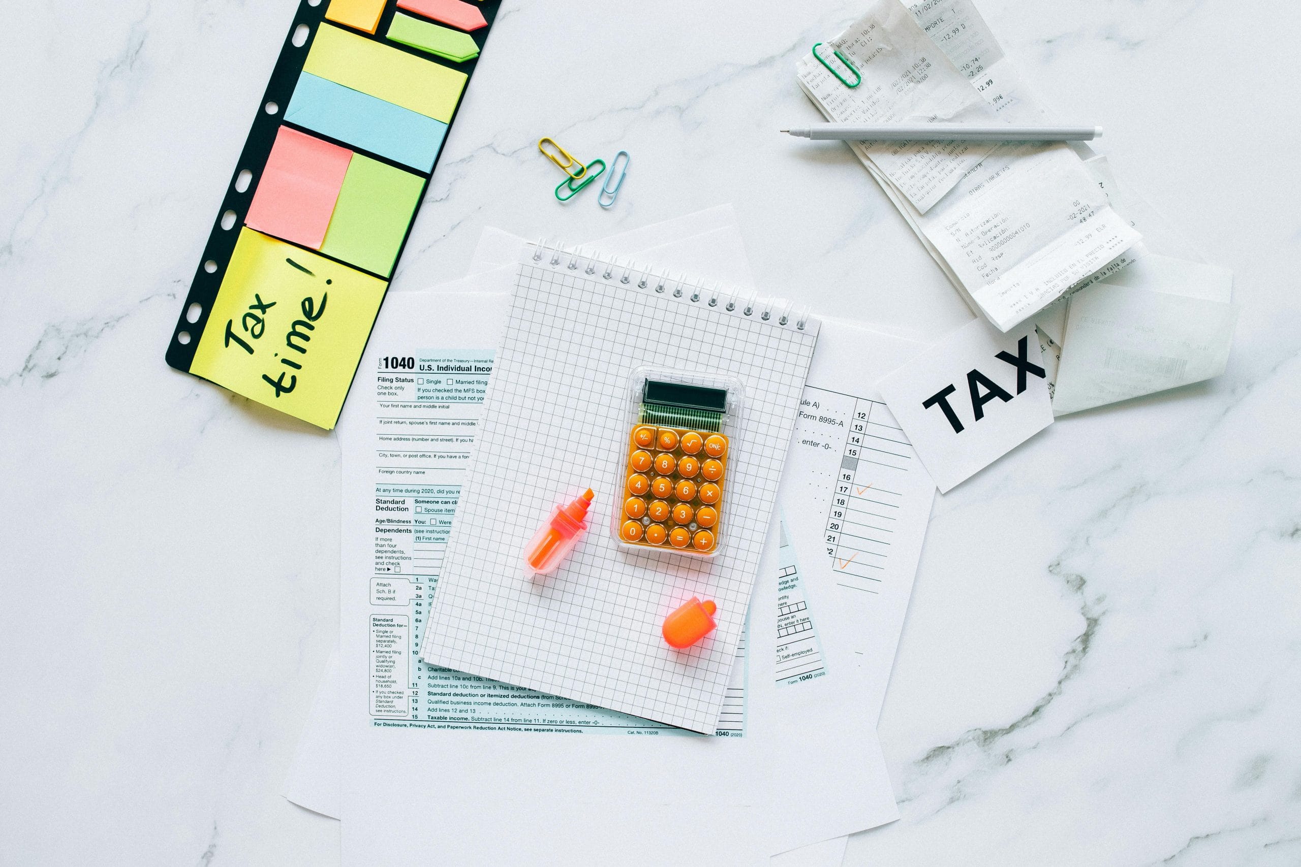 Services Flat lay of tax preparation essentials with calculator, forms, and colorful sticky notes.